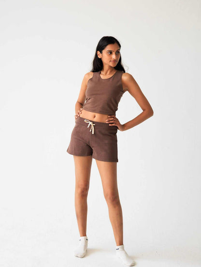 Woman wearing a brown tank top and shorts set on a white background