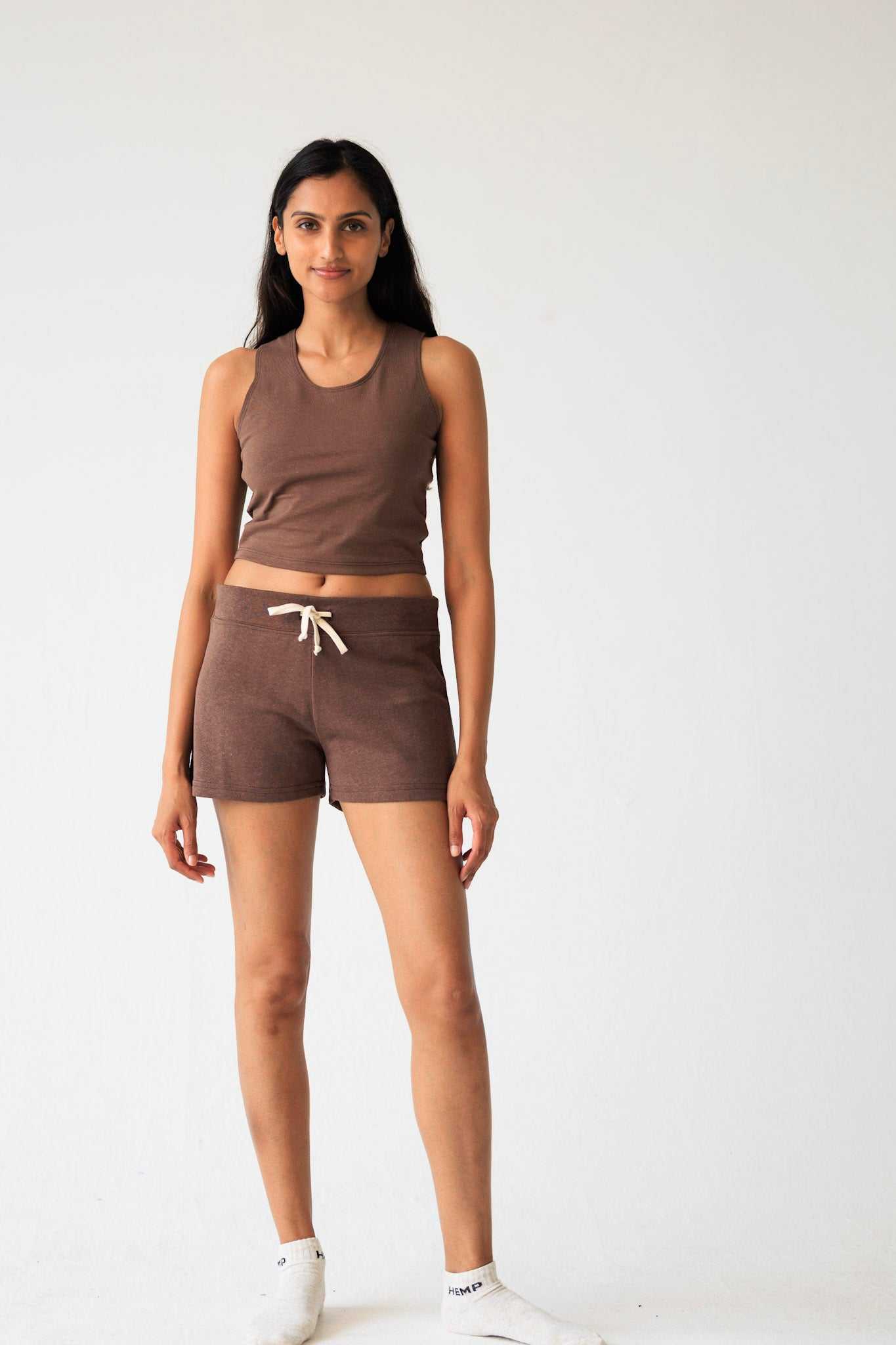 Woman wearing a brown tank top and shorts set on a white background