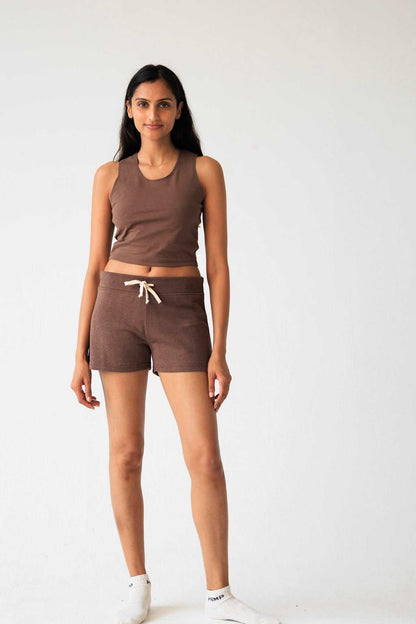Woman wearing a brown tank top and shorts set on a white background