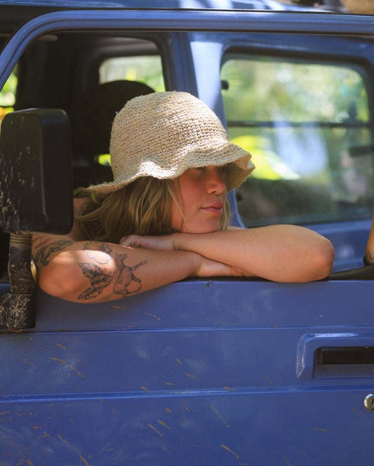 Hemp crochet floppy beach hat in natural color worn by a person sitting in a blue vehicle, showcasing boho style and foldable design.