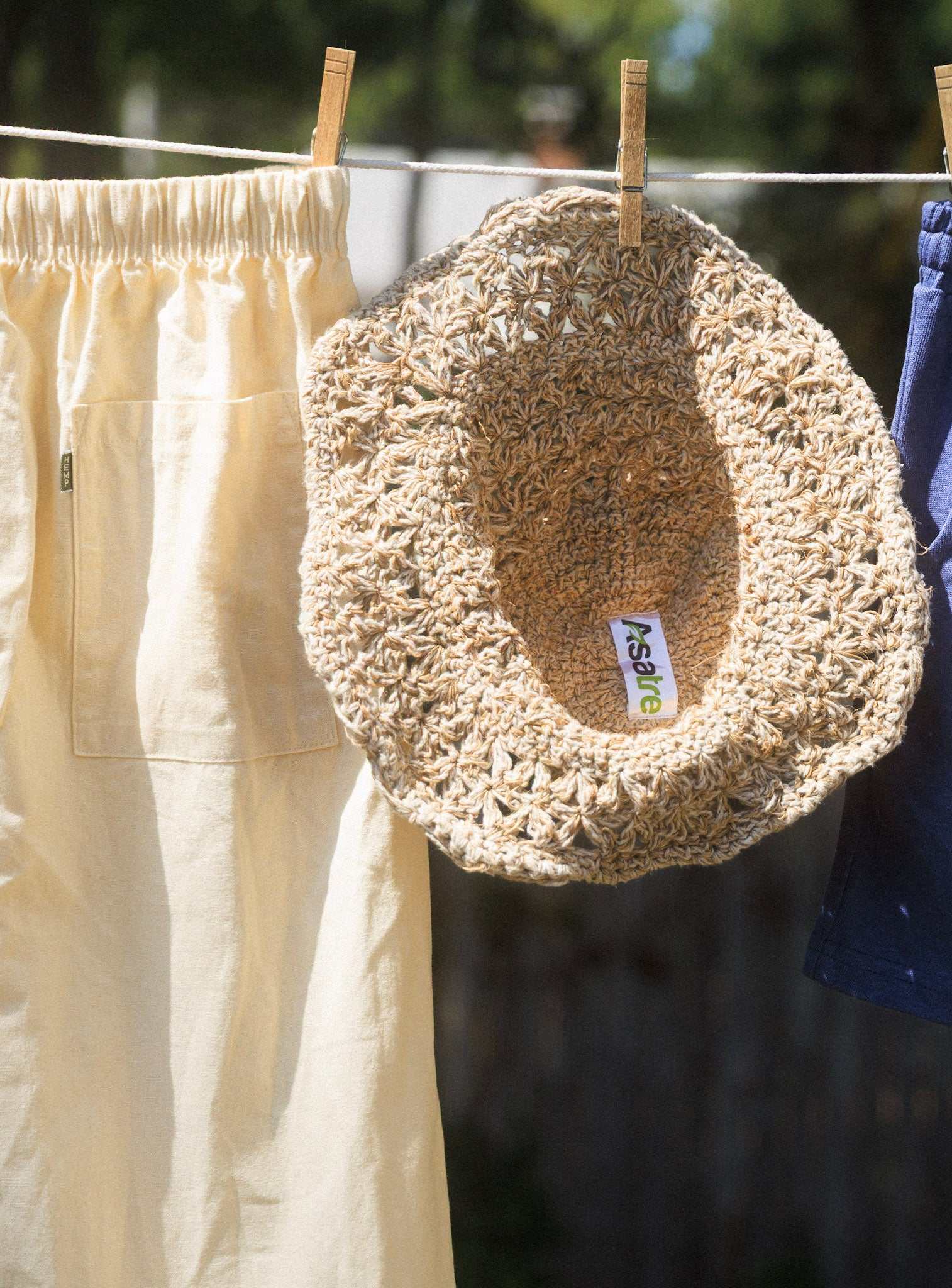 Handmade hemp crochet sun hat with wide brim hanging on clothesline for sun protection