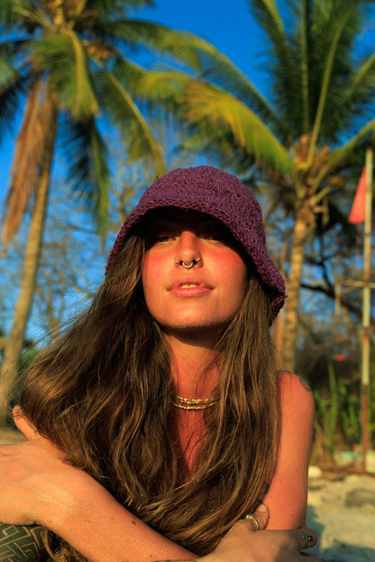 Woman wearing a purple hat with palm trees in the background