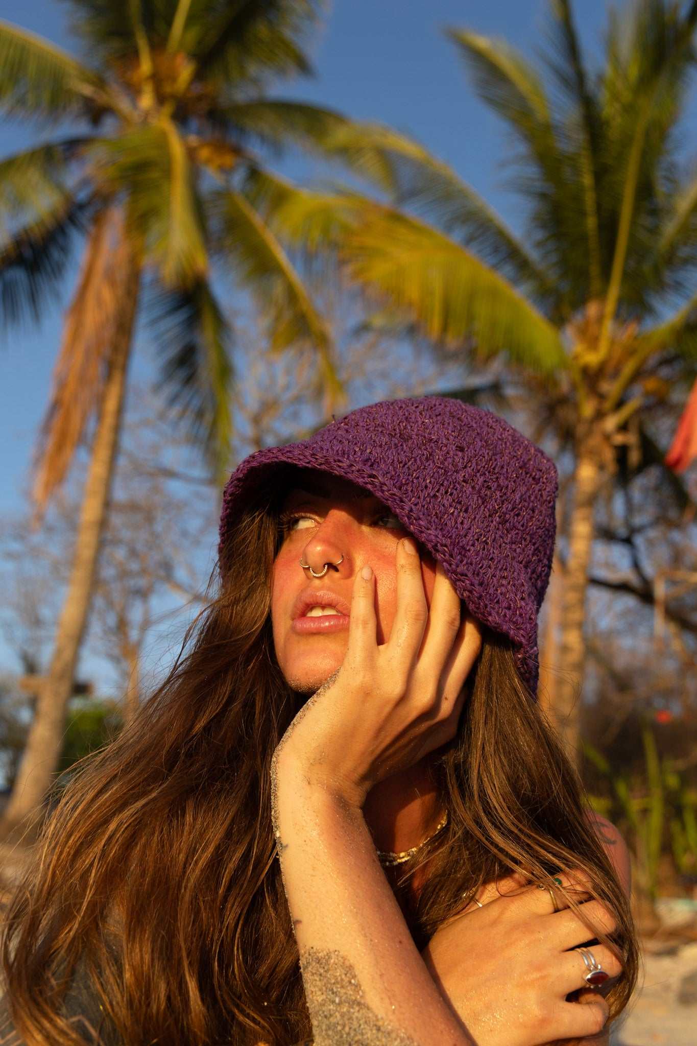 Woman wearing a purple hat with palm trees in the background
