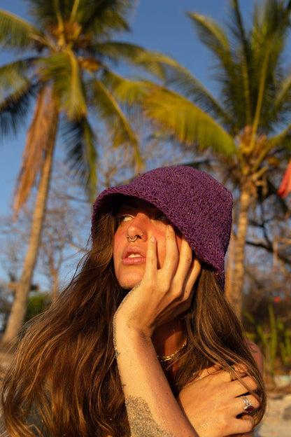 Woman wearing a purple hat with palm trees in the background