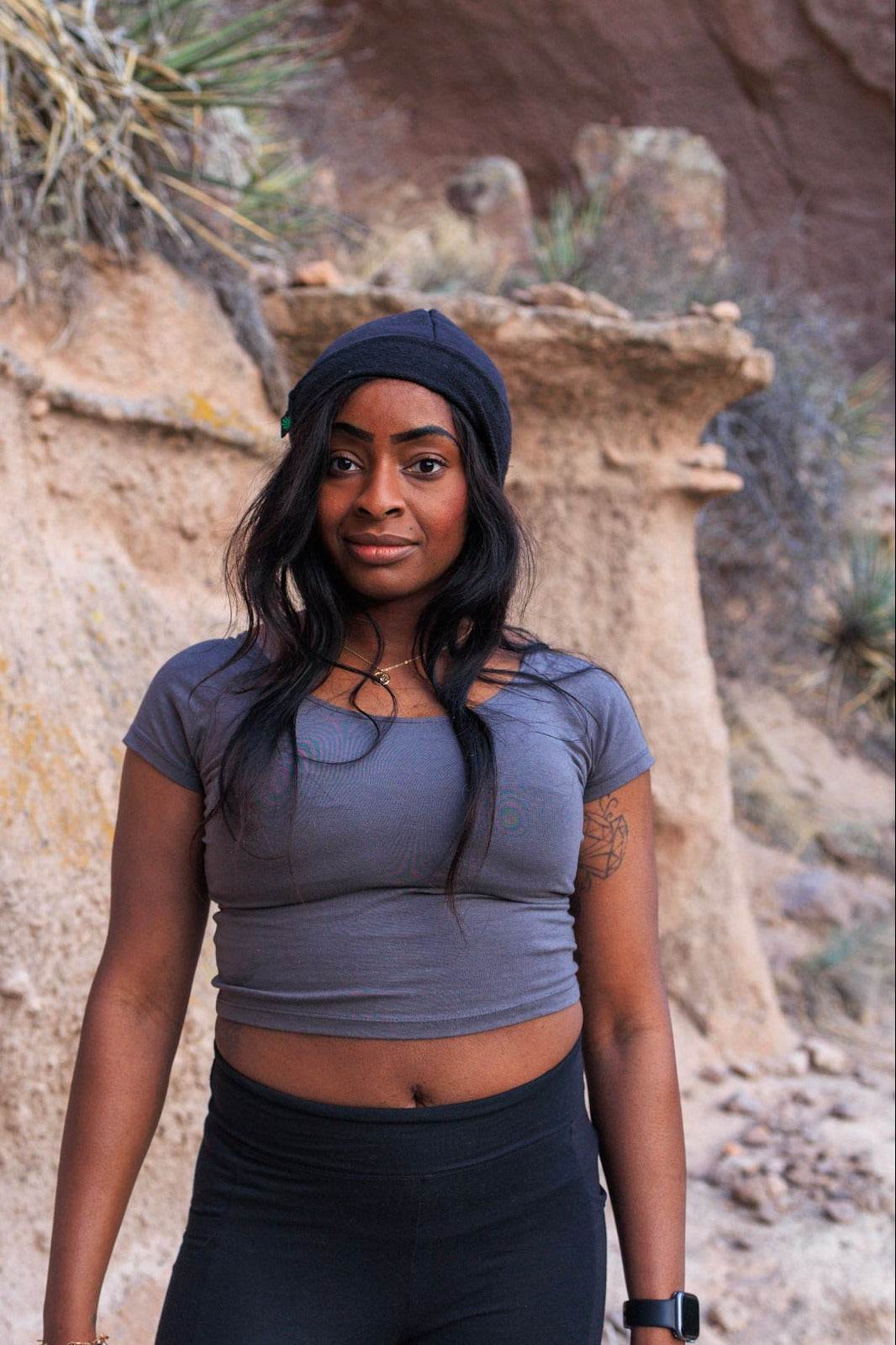 Woman in athletic wear standing in front of a natural rock formation