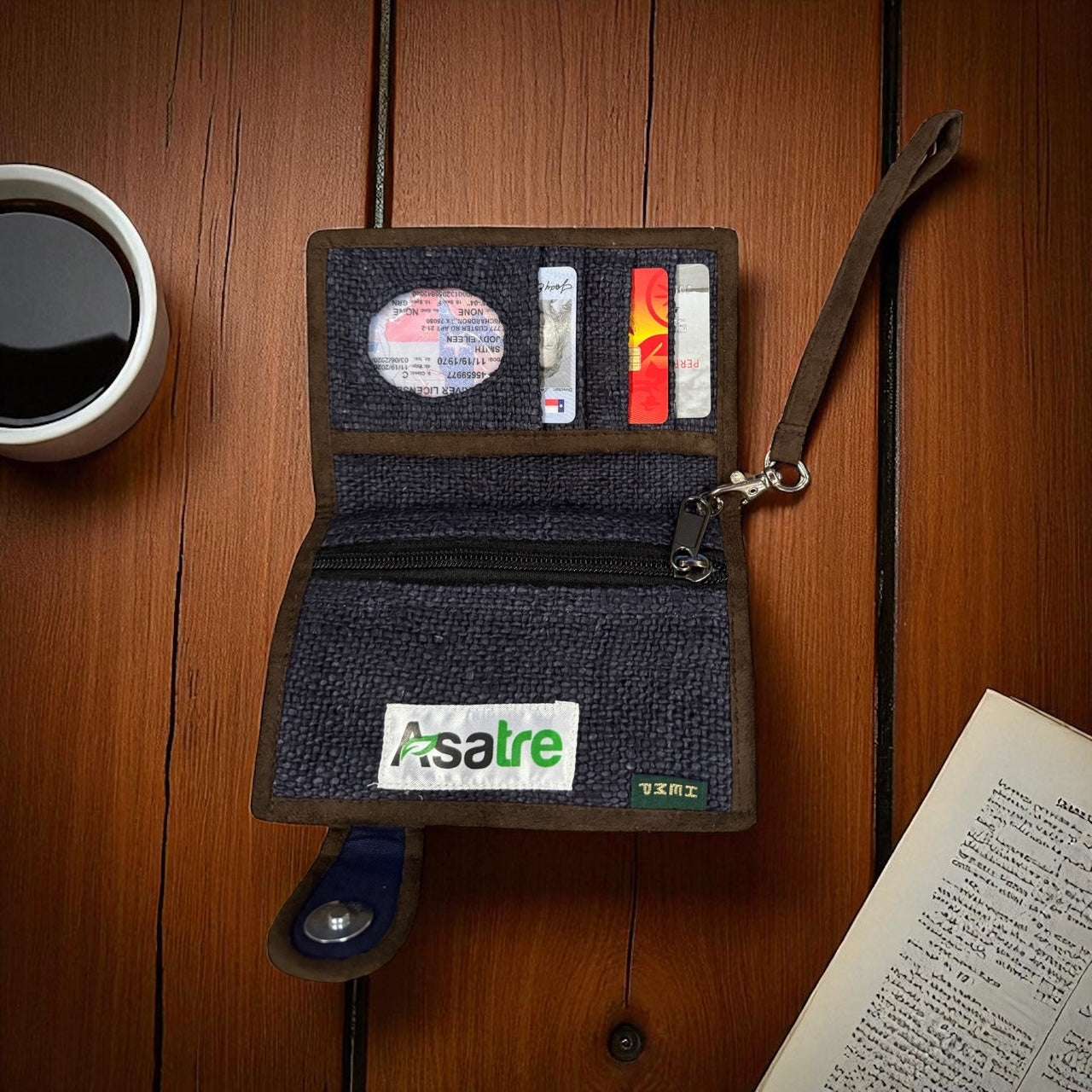 Open wallet with cards on a wooden surface next to a cup of coffee and a book.
