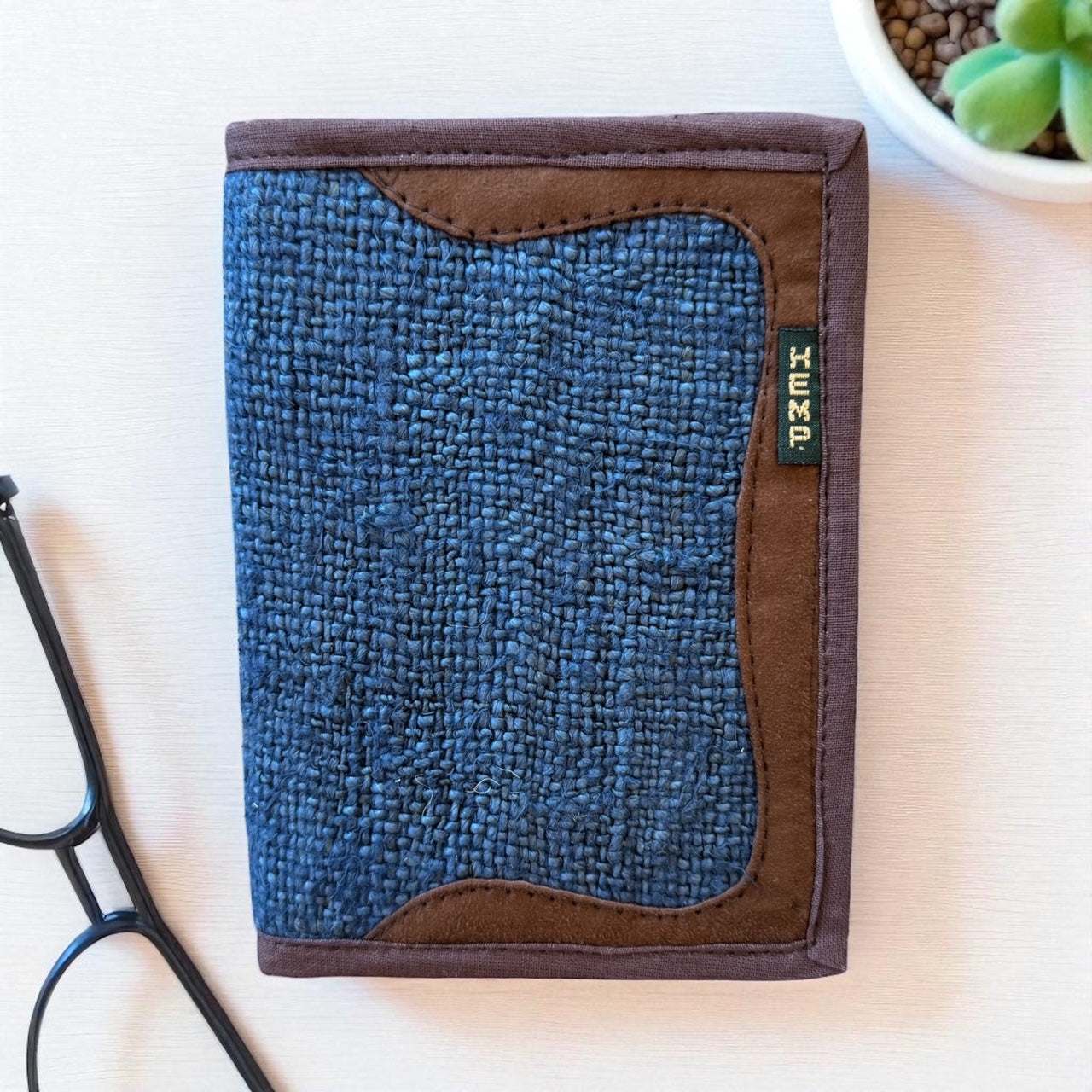 Blue textured wallet with brown border and 'Hemp' label on a light surface.