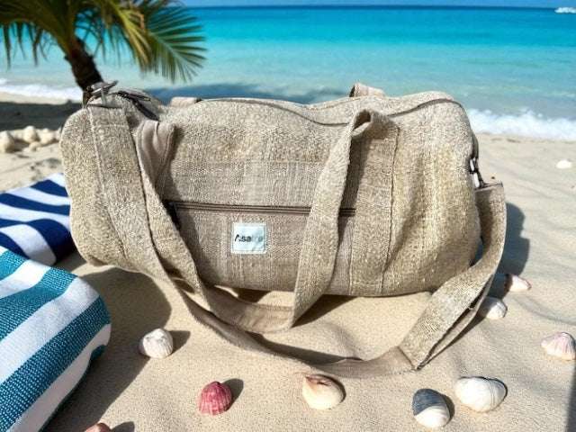 Eco-friendly hemp duffel bag with adjustable shoulder strap and spacious compartments on sandy beach near ocean