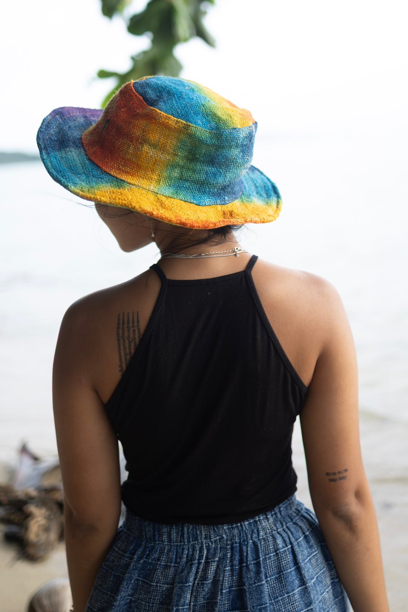 Rainbow tie dye hemp bucket hat worn outdoors, handmade eco-friendly sun hat style.