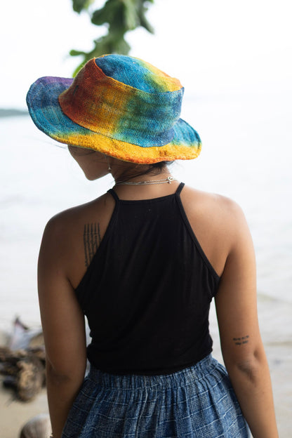 Rainbow tie dye hemp bucket hat worn outdoors, handmade eco-friendly sun hat style.