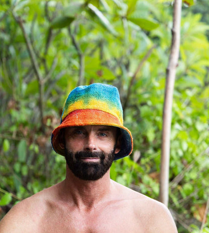 Man wearing a colorful bucket hat in a forest setting