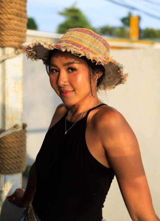 woman wearing hemp sun hat with multi color stripes and frayed brim outdoors