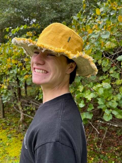 Person wearing a yellow hat with a green leafy background