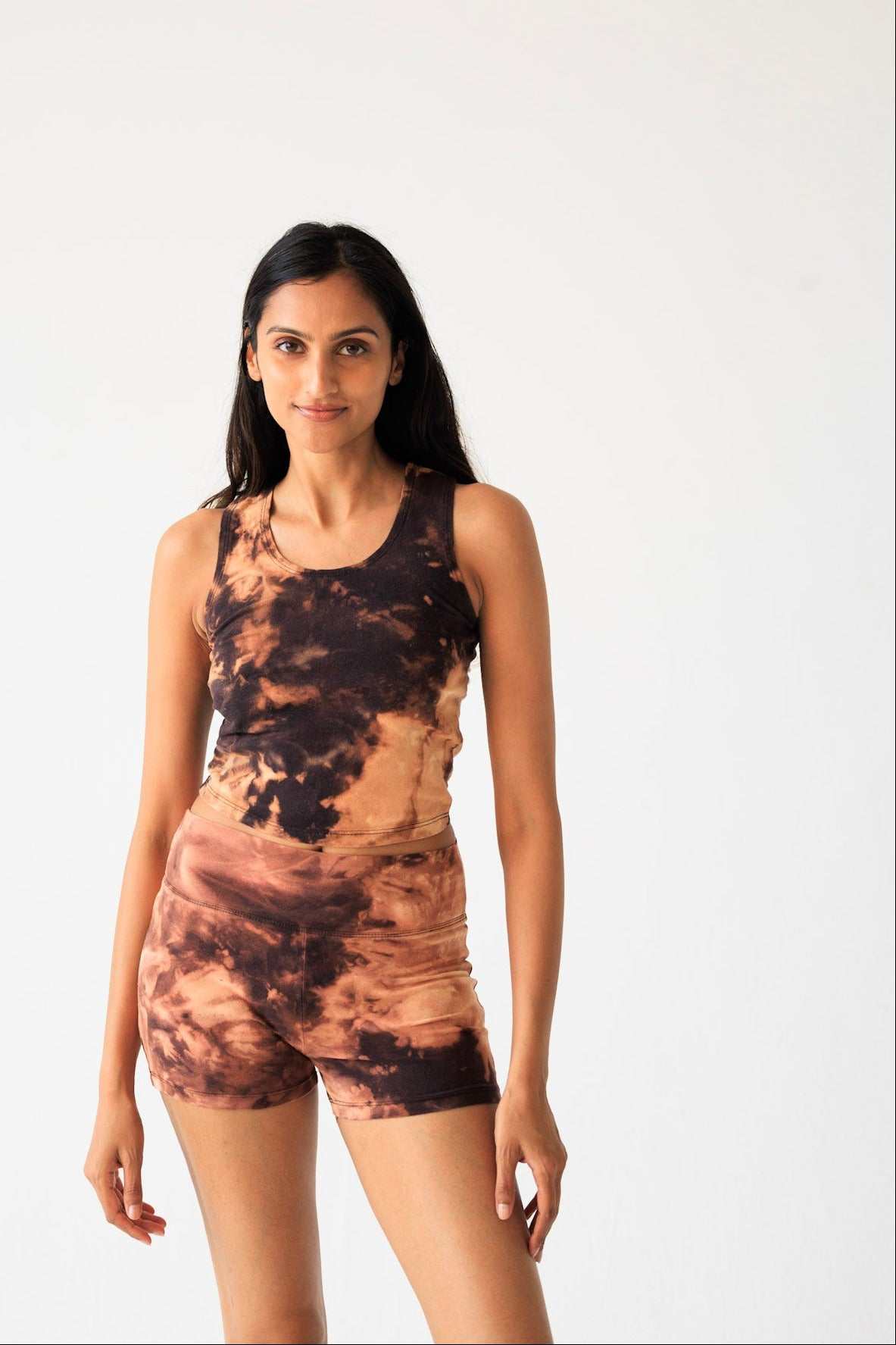 Woman wearing a tie-dye tank top and shorts on a white background