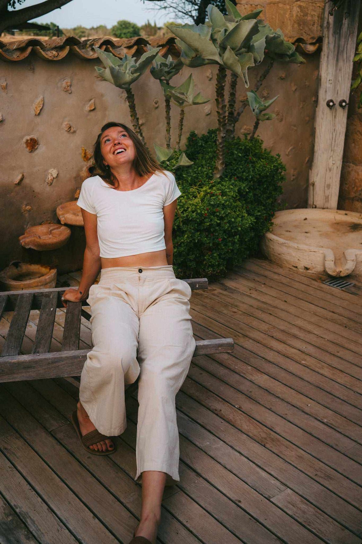 Cotton Crop Top in white, with short sleeves, a scoop neckline, and a fitted cropped hem, worn with light trousers