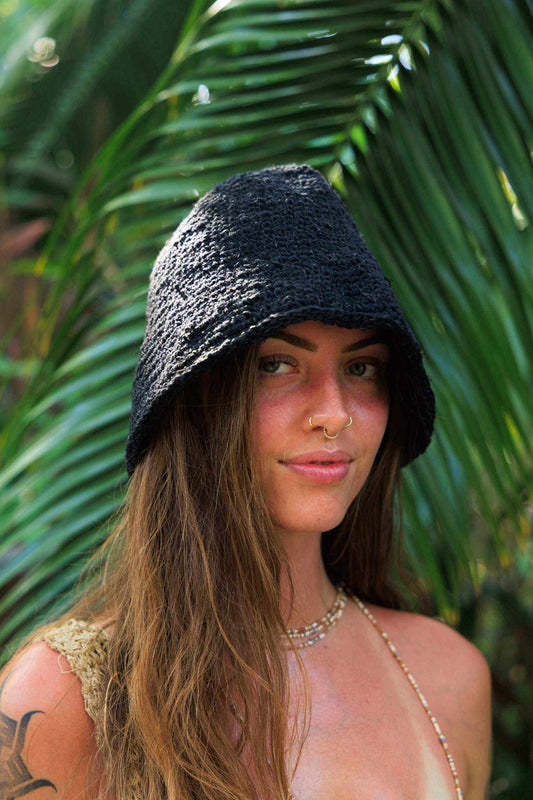 Festival crochet hat in black textured open-knit yarn, worn as a soft hood with a pointed draped shape
