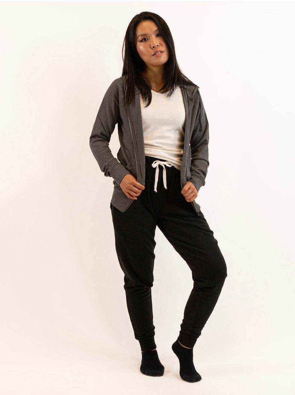 Hemp hoodie in charcoal gray jersey with a full-zip front, worn open over a white top with black joggers