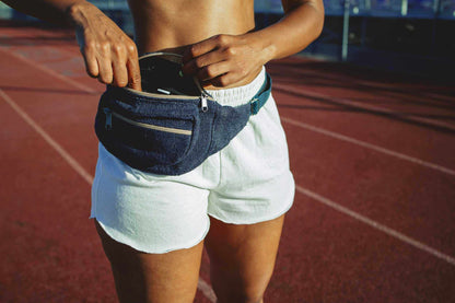 Hemp running shorts in white jersey with a relaxed fit and curved hems, worn with a navy waist pack