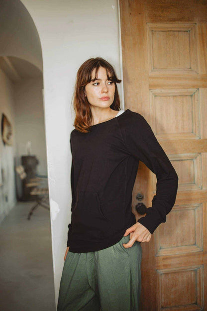Hemp Sweatshirt Women in black with long sleeves, relaxed neckline and exposed seam detailing, paired with olive trousers