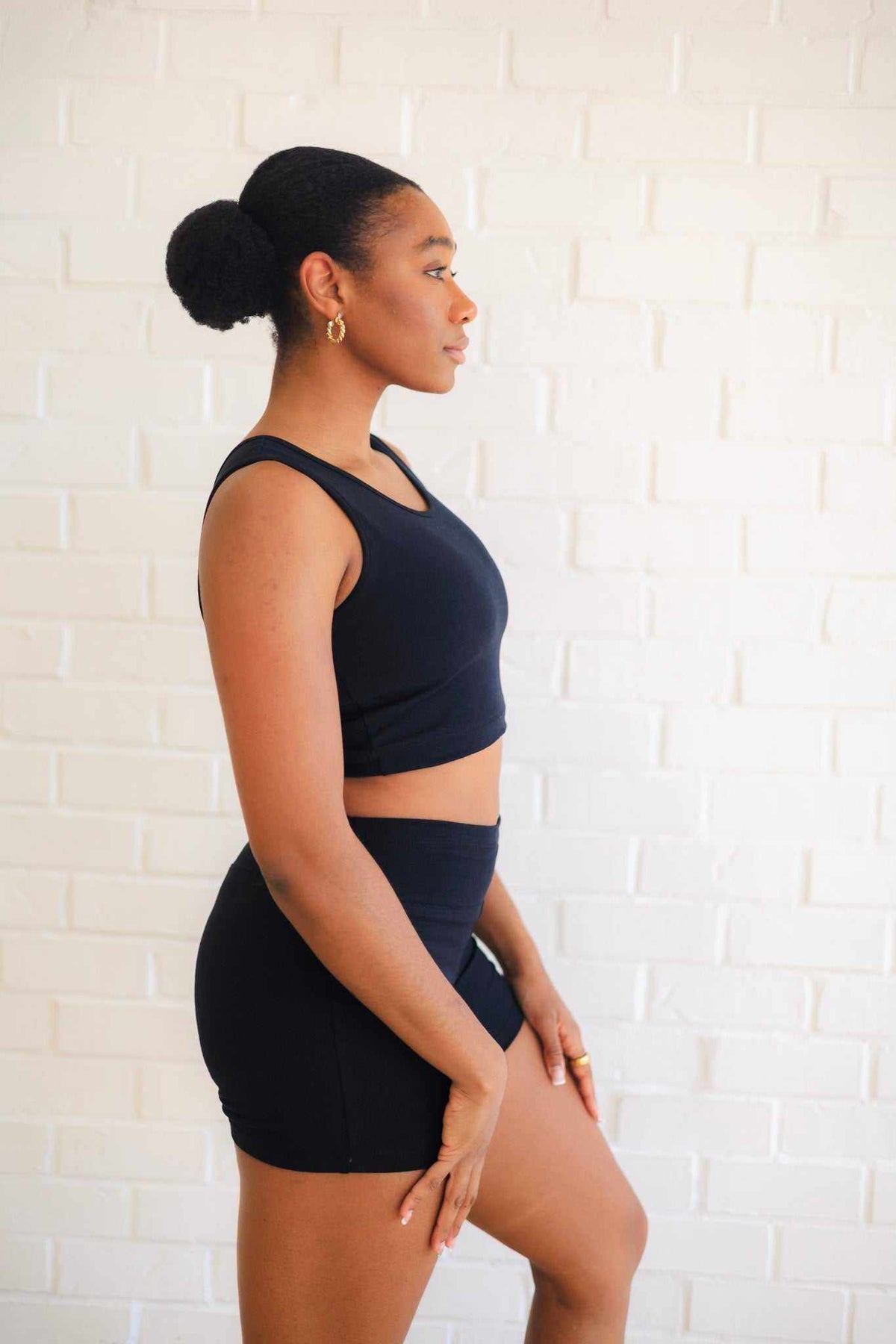 Women's Yoga Shorts in black stretch fabric, fitted with a wide yoga waistband and short inseam, paired with a crop top