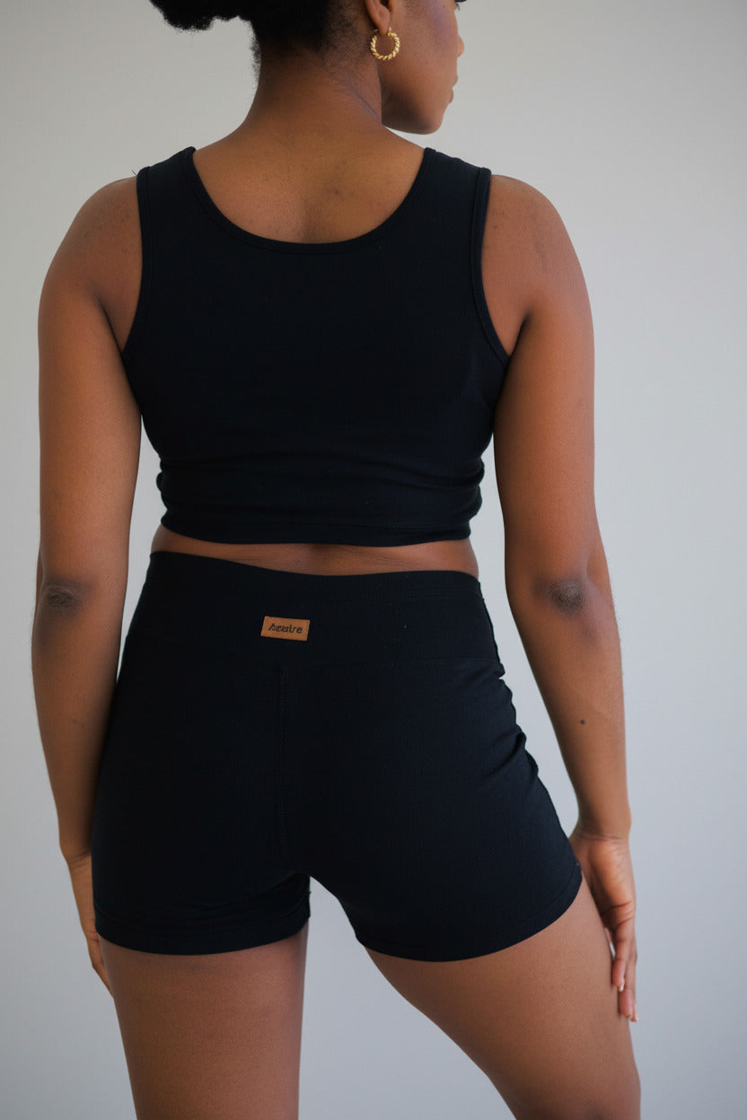 Women's Yoga Shorts in black fitted stretch fabric with a wide waistband and short inseam, shown worn with a matching crop top