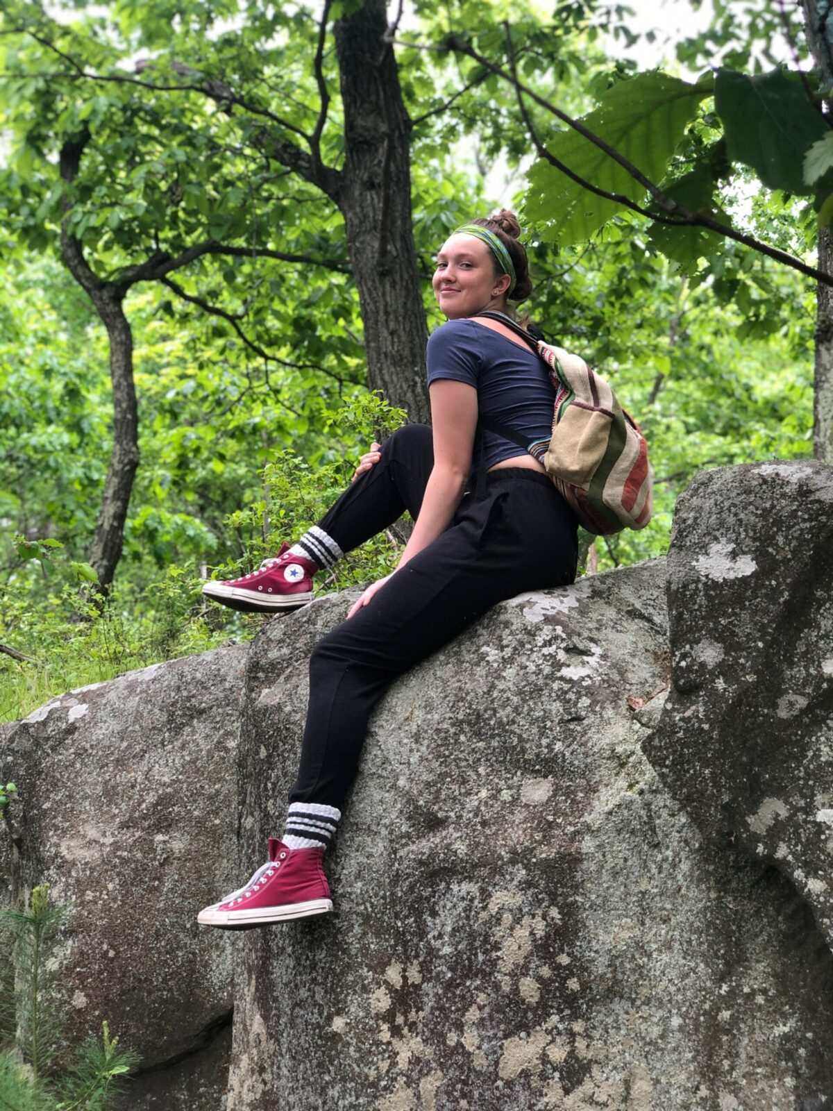 Woman wearing black hemp joggers sitting on a rock in nature